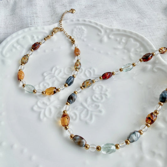 Necklace and bracelet with multicolored beads on a white textured surface