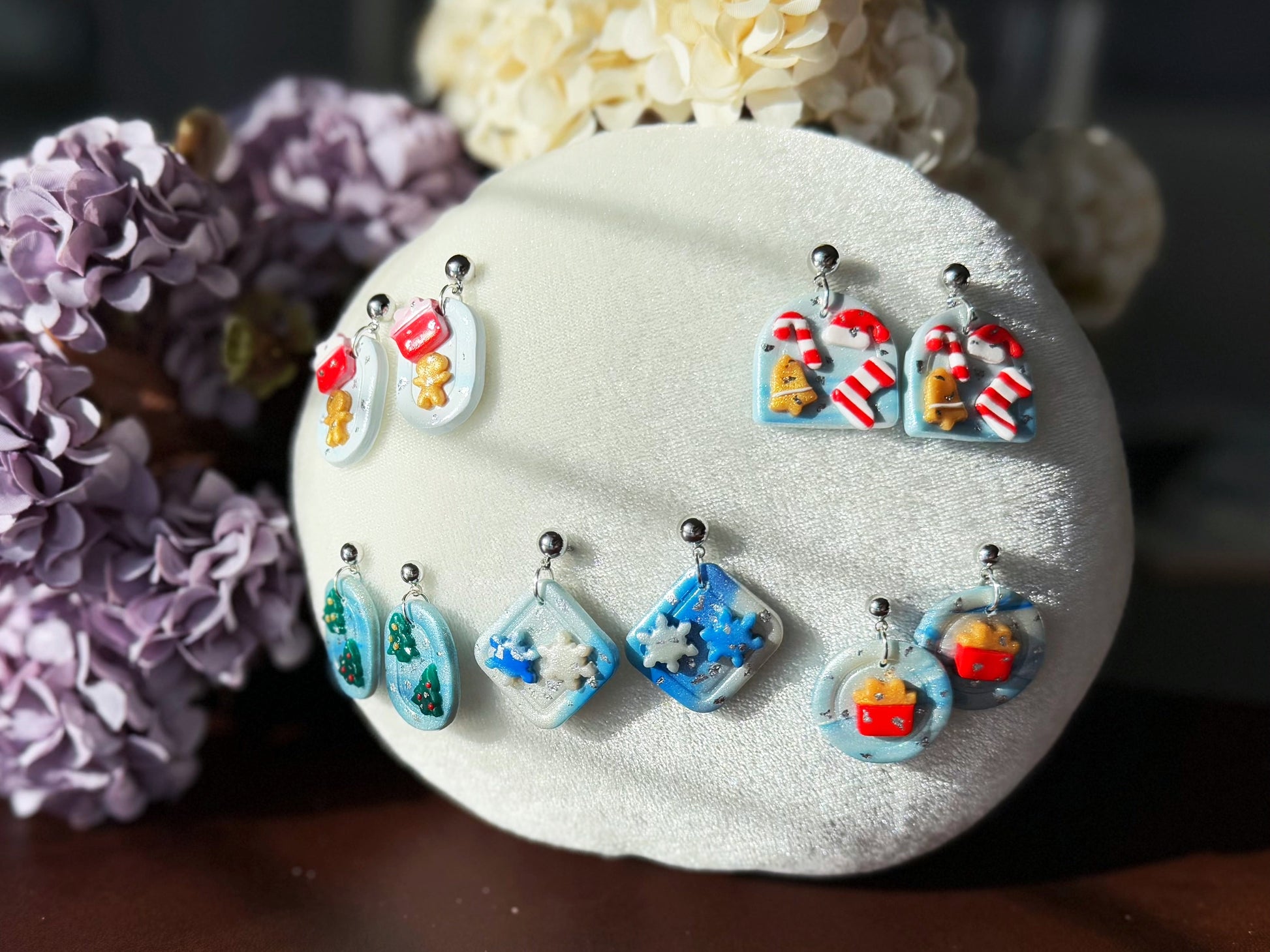 Colorful earrings displayed on a white stone with flowers in the background