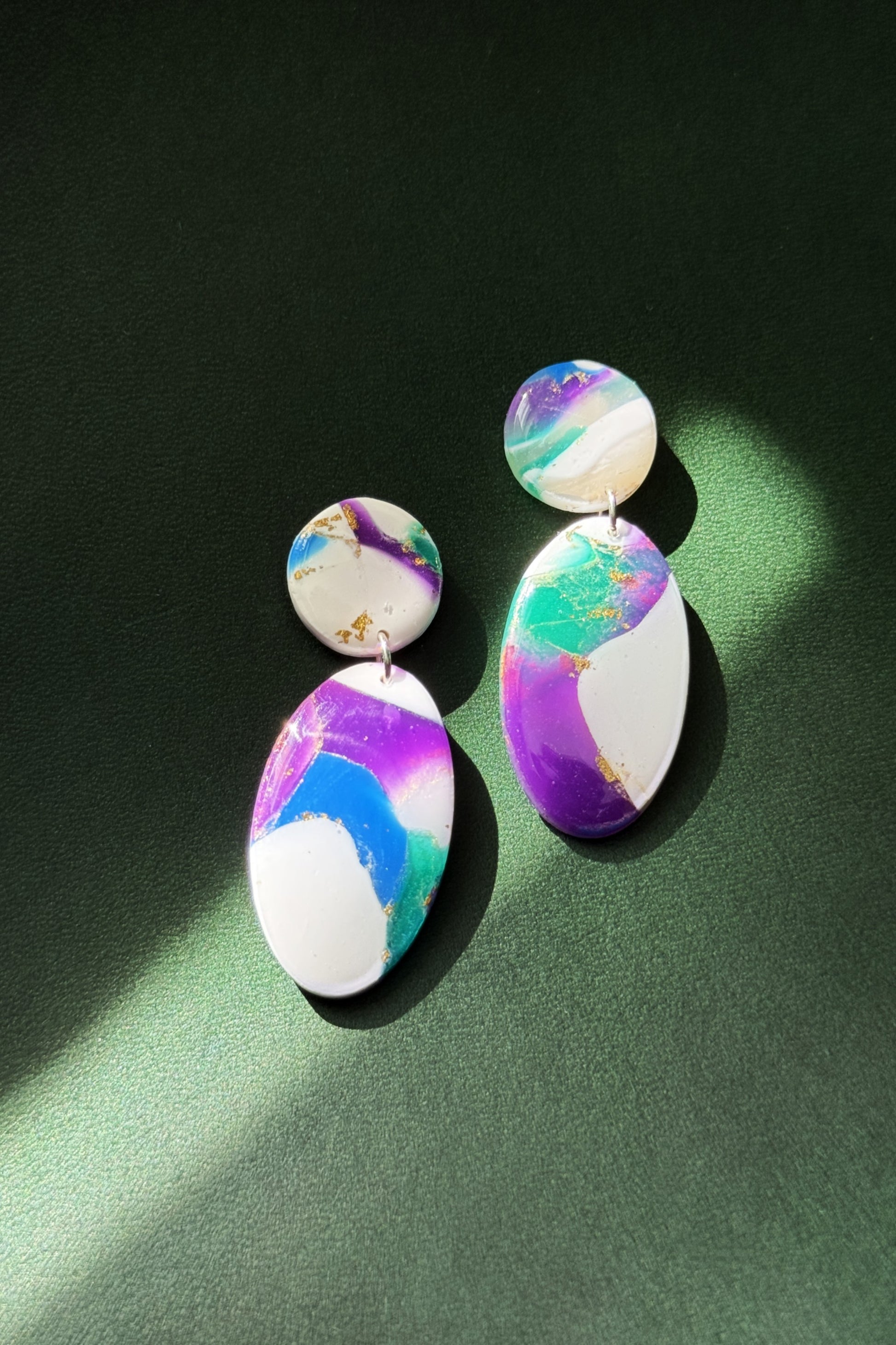 Handmade earrings with marble-like pattern in blue, green, purple, and white, accented with gold leaf, evoking the colors of the aurora in the night sky.
