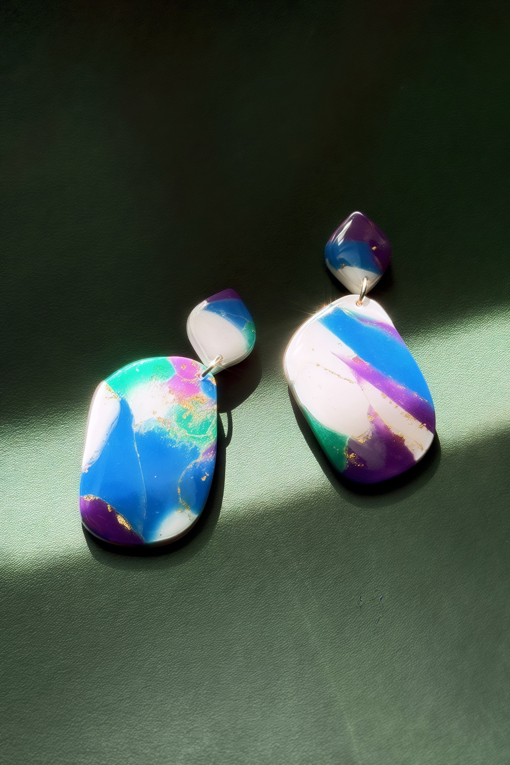 Handmade earrings with marble-like pattern in blue, green, purple, and white, accented with gold leaf, evoking the colors of the aurora in the night sky.