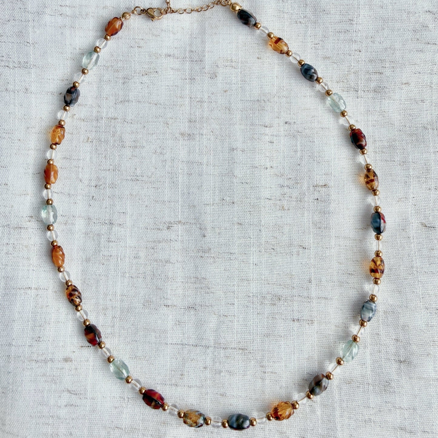 Necklace with multicolored beads on a textured fabric background