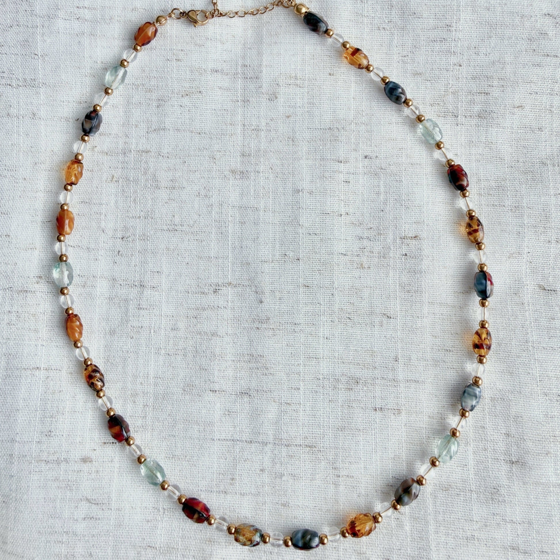 Necklace with multicolored beads on a textured fabric background