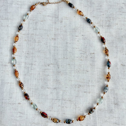 Necklace with multicolored beads on a textured fabric background