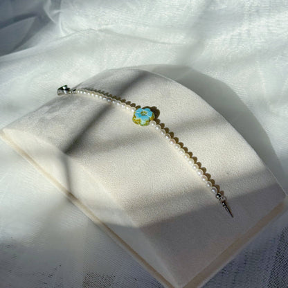 Pearl beaded bracelet with a blue Czech glass floral centerpiece, minimalist handmade jewelry on a soft fabric background