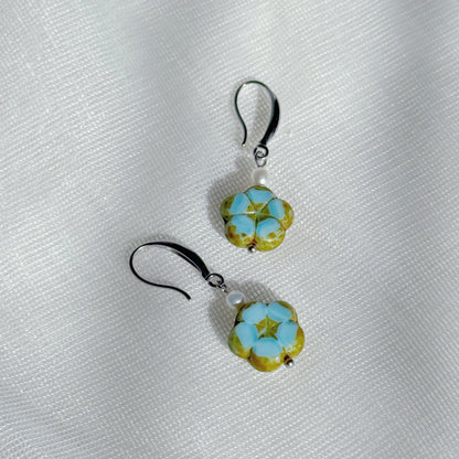 Pearl drop earrings with blue Czech glass floral charms, minimalist lightweight handmade jewelry on a soft fabric background