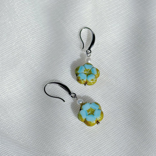 Pearl drop earrings with blue Czech glass floral charms, minimalist lightweight handmade jewelry on a soft fabric background