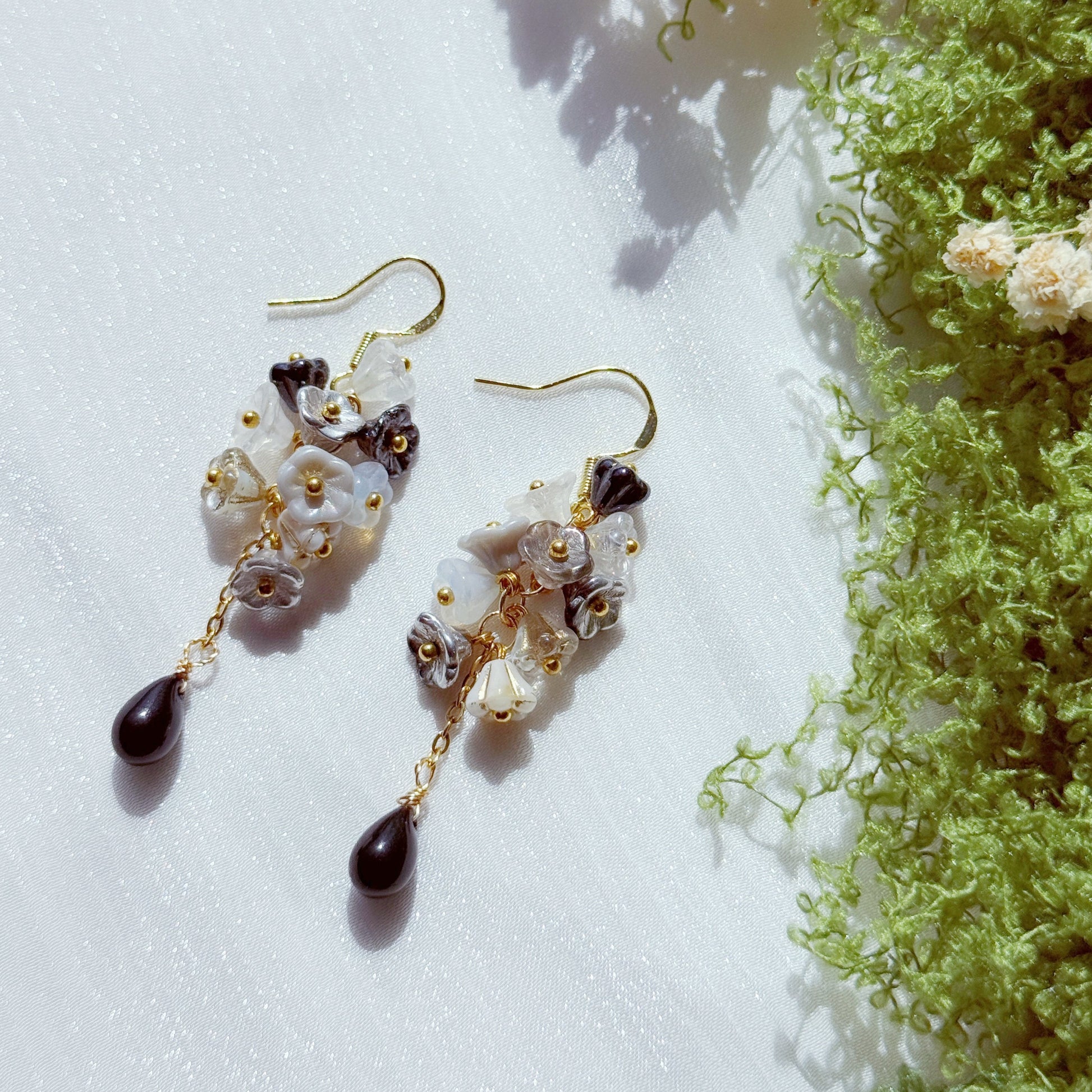 Handmade Czech glass flower cluster earrings in black, white, and neutral tones, featuring layered floral beads and a dark teardrop drop, soft contrast with a moody, elegant feel.