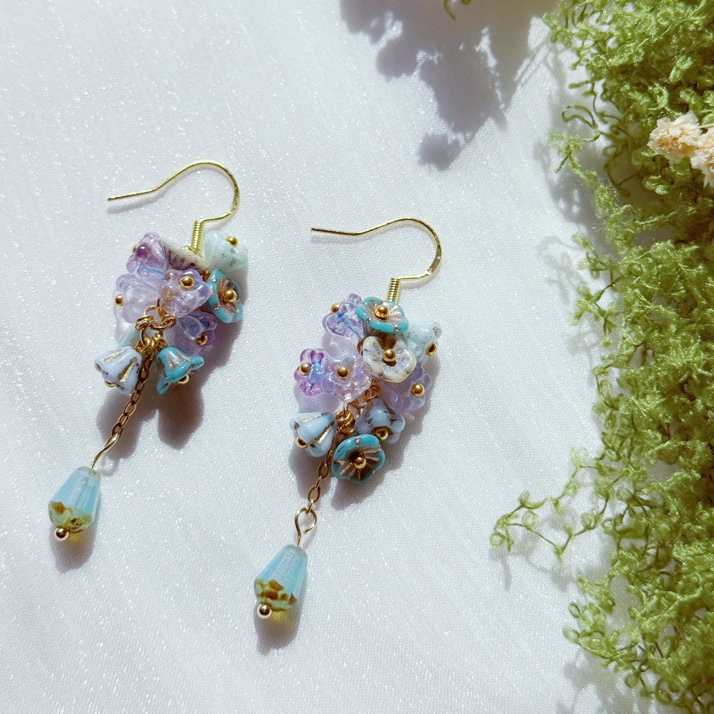 Handmade Czech glass flower cluster earrings in pastel purple and blue tones, featuring small floral bead clusters and a soft blue teardrop detail, airy and dreamy design.