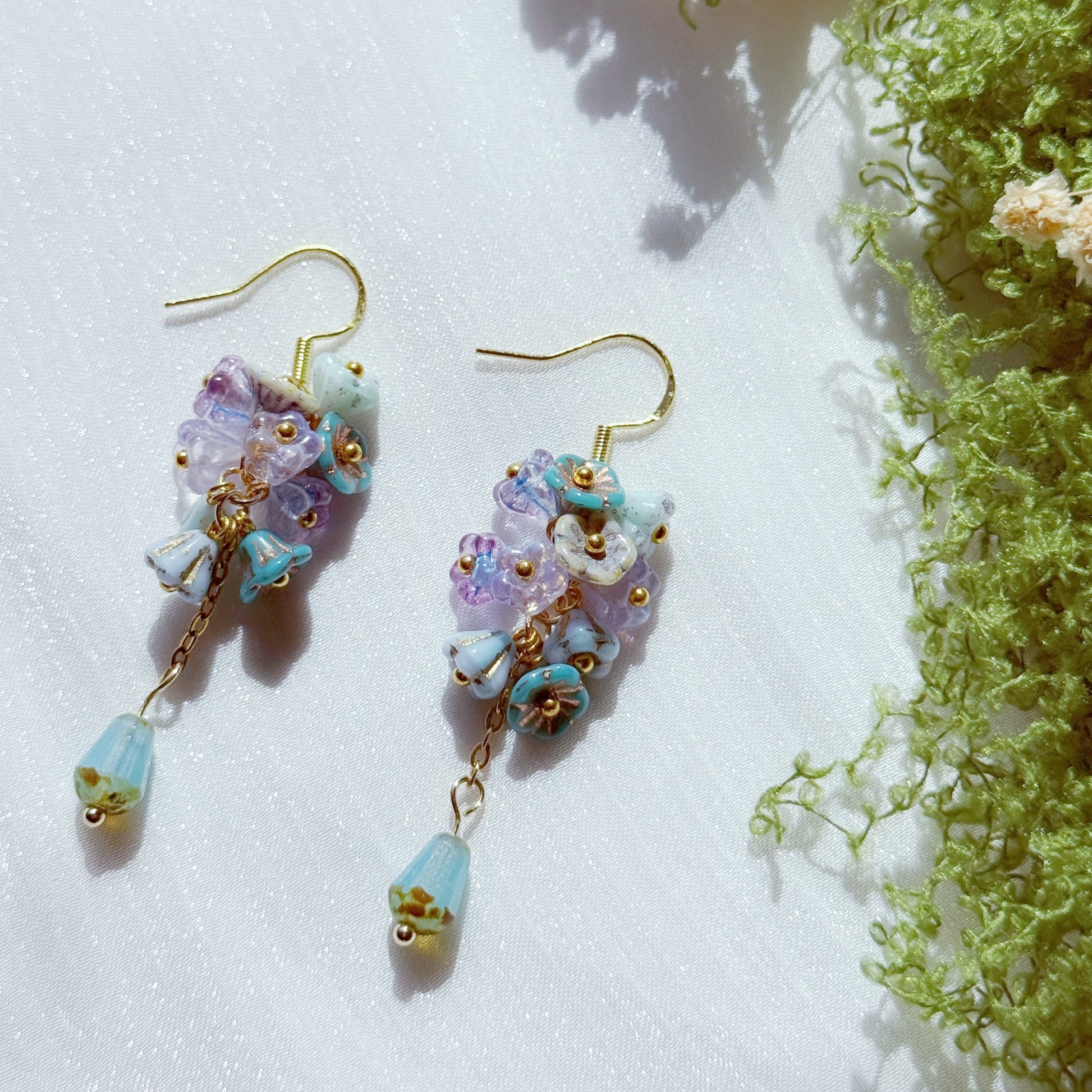 Handmade Czech glass flower cluster earrings in pastel purple and blue tones, featuring small floral bead clusters and a soft blue teardrop detail, airy and dreamy design.