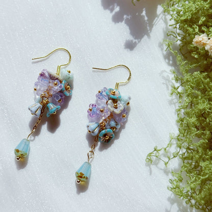 Handmade Czech glass flower cluster earrings in pastel purple and blue tones, featuring small floral bead clusters and a soft blue teardrop detail, airy and dreamy design.