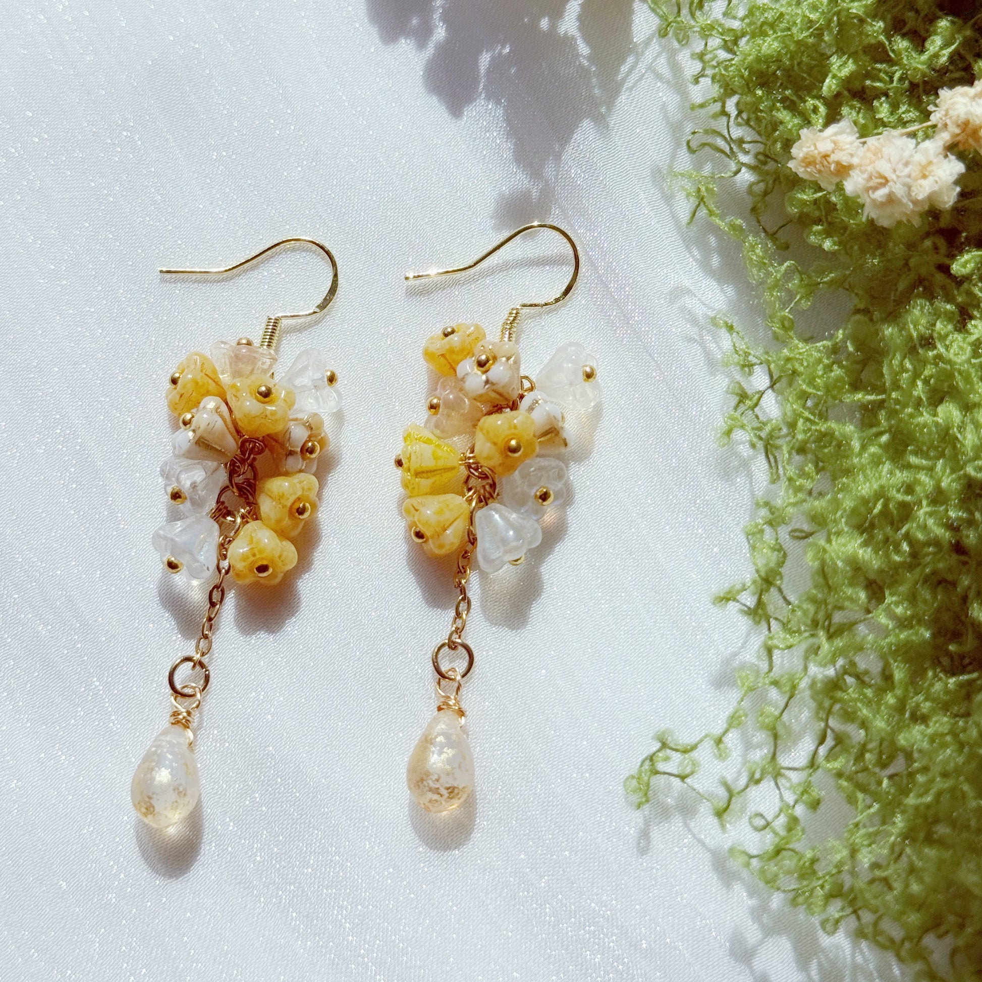 Handmade Czech glass flower cluster earrings in soft yellow and white tones, featuring clustered floral beads and a translucent teardrop drop, light and warm spring-inspired design.
