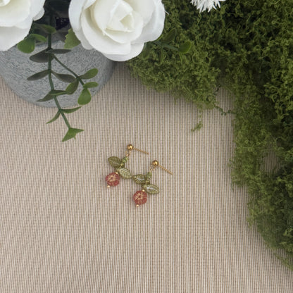 Beaded flower earring on a textured surface with flowers and greenery in the background