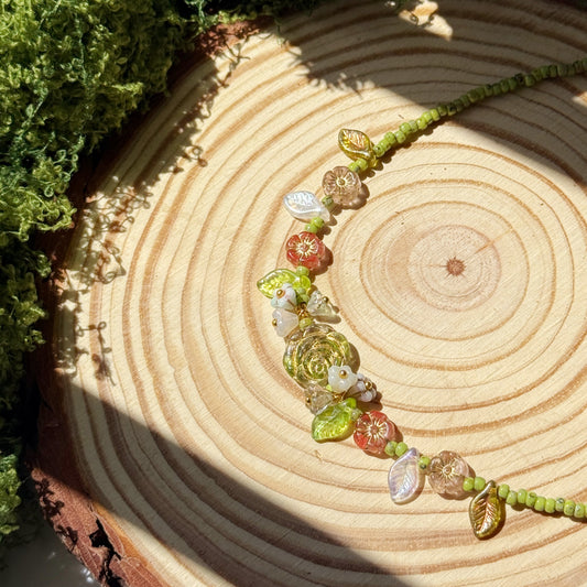 Choker with green and floral beads on a wooden surface with moss