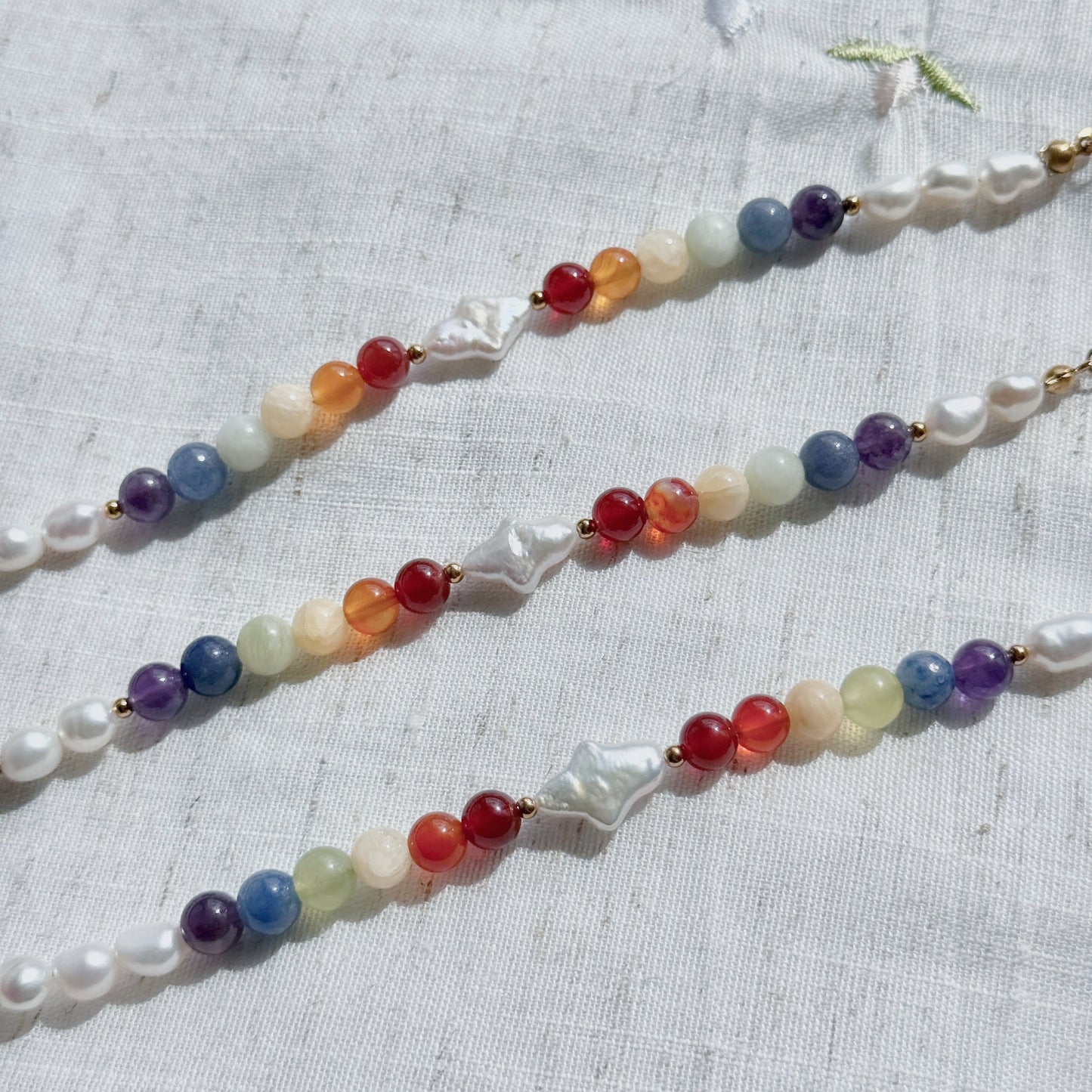 Multicolored natural stone beaded bracelets on a textured fabric background