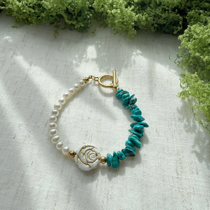Handmade bracelet featuring natural turquoise, freshwater pearls, and Czech glass rose beads displayed on a soft linen background.