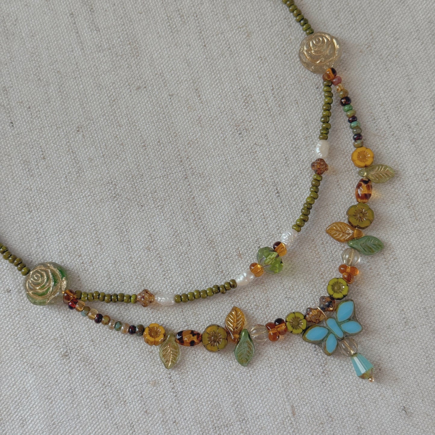vintage tone double layered necklace with a blue butterfly pendant on a white surface