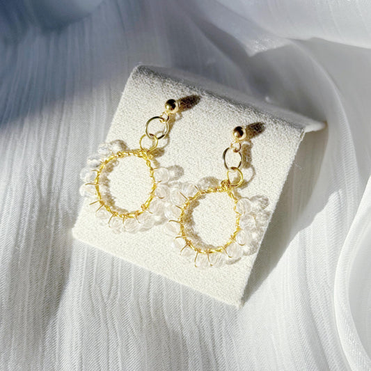 Clear quartz wire wrapped circle earrings on a soft silk background