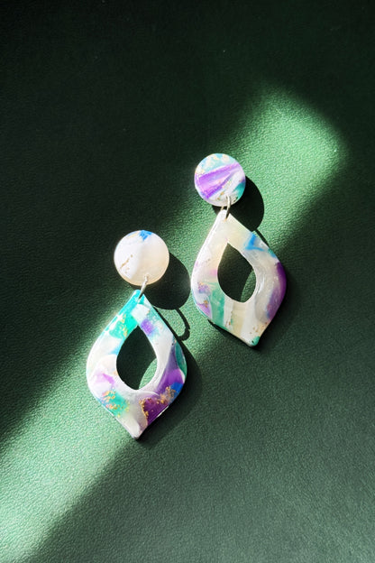 Handmade earrings with marble-like pattern in blue, green, purple, and white, accented with gold leaf, evoking the colors of the aurora in the night sky.