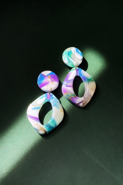 Handmade earrings with marble-like pattern in blue, green, purple, and white, accented with gold leaf, evoking the colors of the aurora in the night sky.